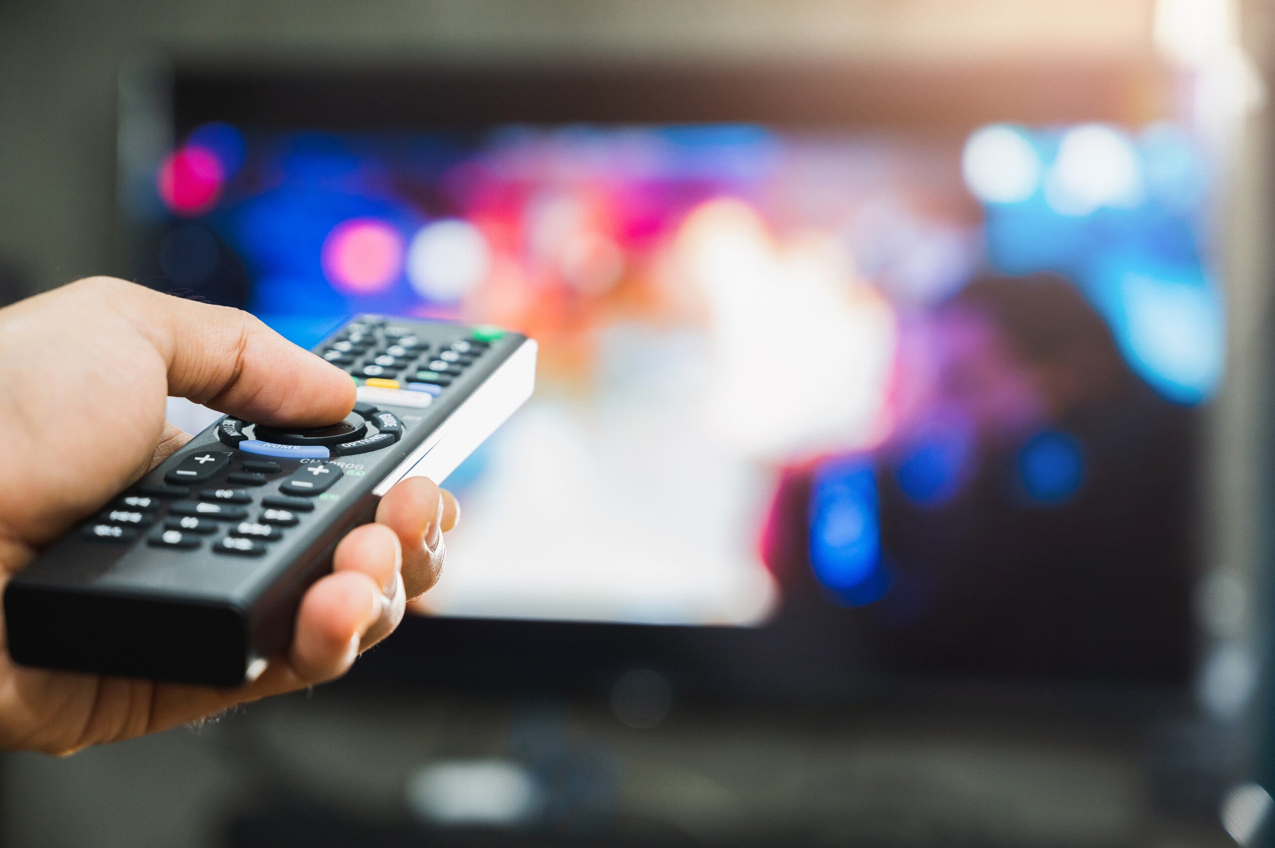 Young man holding television remote control. Hands pointing to tv screen set and turning it on or off select channel watching tv on his sofa at home in the living room relax. (WISH Photo, File)