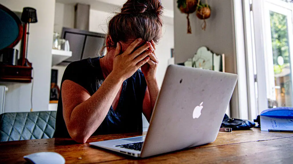 In this photo illustration a woman appears to be stressed or dealing with mental health issues as she sits in front of a laptop computer. (Photo Illustration by Robin Utrecht/SOPA Images/LightRocket via Getty Images)