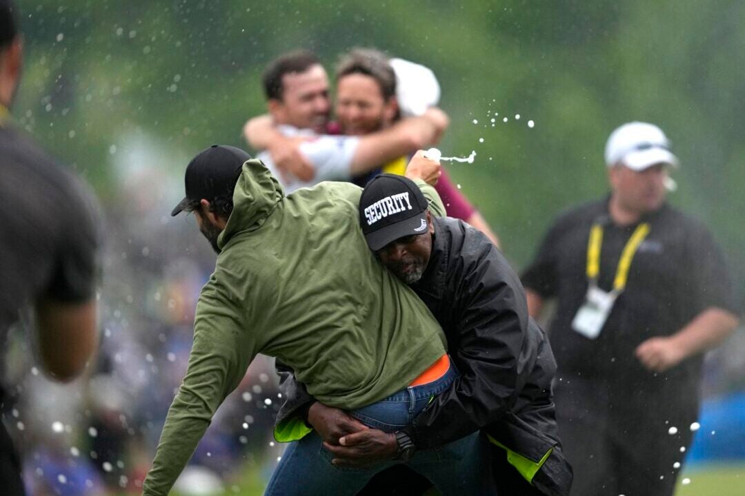 Canadian golfer Adam Hadwin, left, is tackled by a security guard when he tries to celebrate with compatriot Nick Taylor, background left, after Taylor won the Canadian Open in Toronto on Sunday. (Photo by Andrew Lahodynskyj/AP)