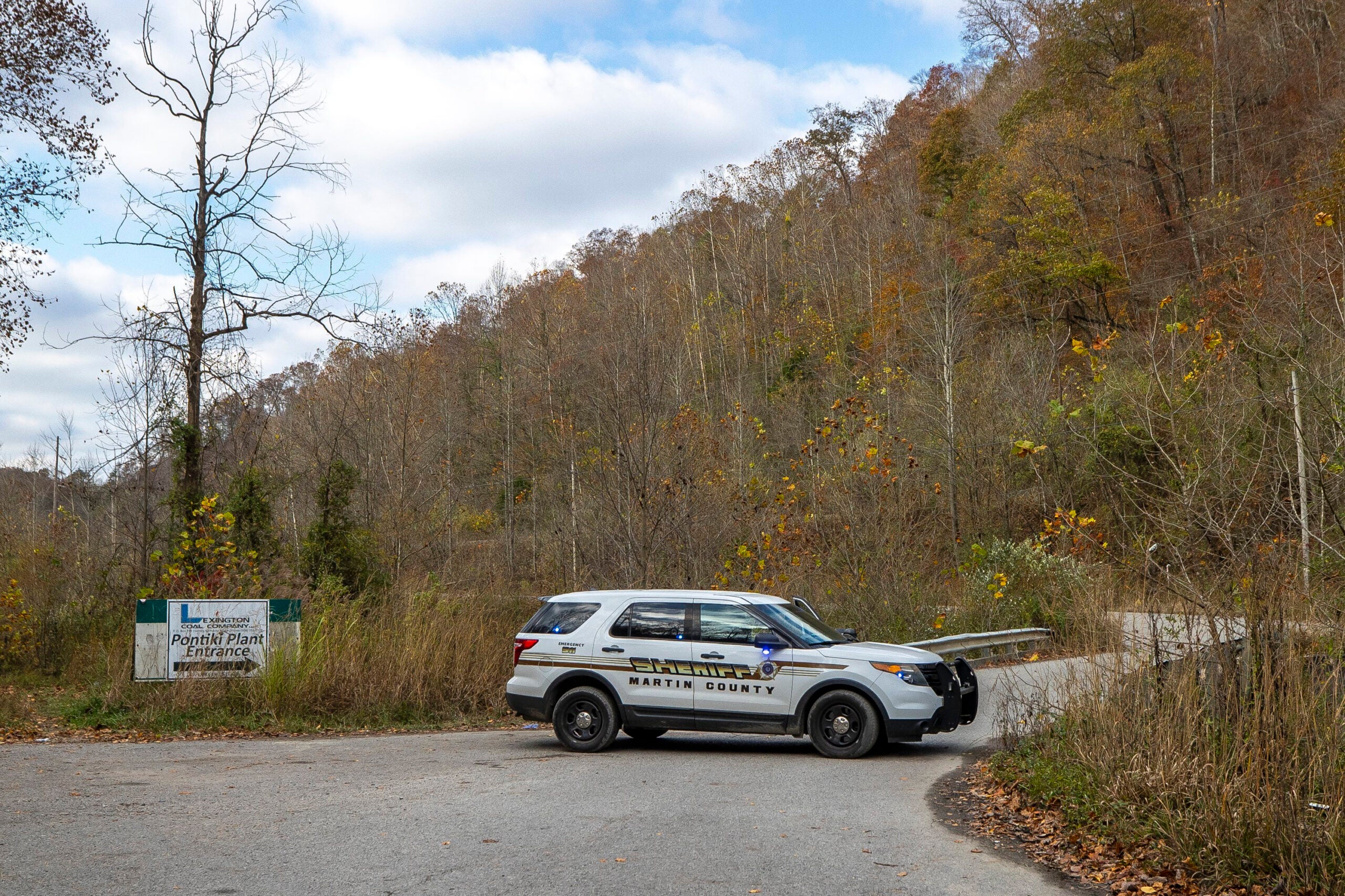 A sheriff's vehicle blocks a road leading to the area where a rescue operation is underway for two workers trapped inside a collapsed coal preparation plant in Martin County, south of Inez, Ky., on Wednesday, Nov. 1, 2023. Kentucky Gov. Andy Beshear says a man has died after he and a coworker were trapped beneath a collapsed 11-story building being demolished at an abandoned mine’s coal preparation plant. (Ryan C. Hermens/Lexington Herald-Leader via AP)