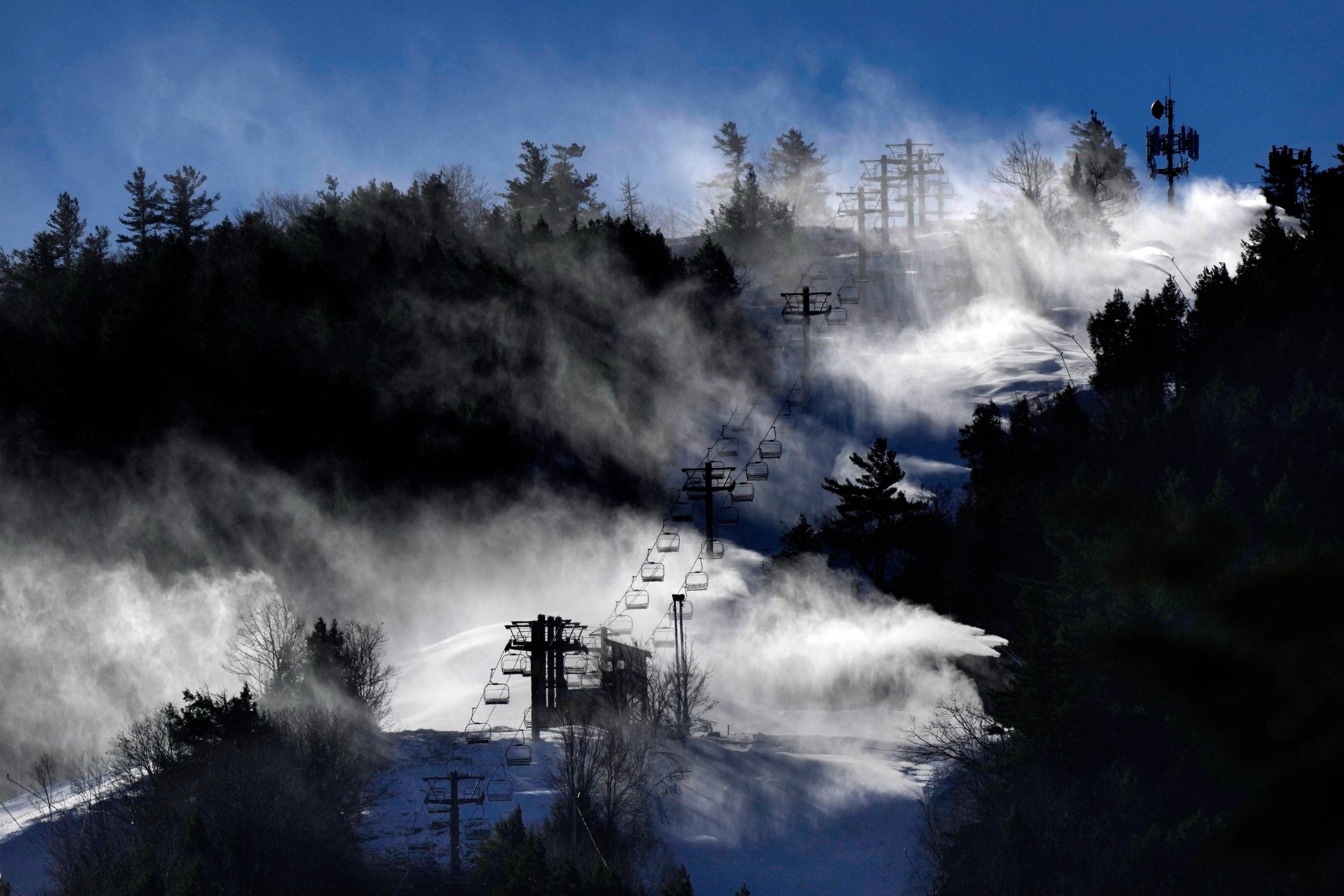 Man-made snow is blown from snowmaking equipment near the summit of Pleasant Mountain ski resort, Thursday, Dec. 21, 2023, in Bridgton, Maine. The New England ski industry is working to recover from a disastrous rain storm that washed away much of the snow just before the Christmas vacation season.