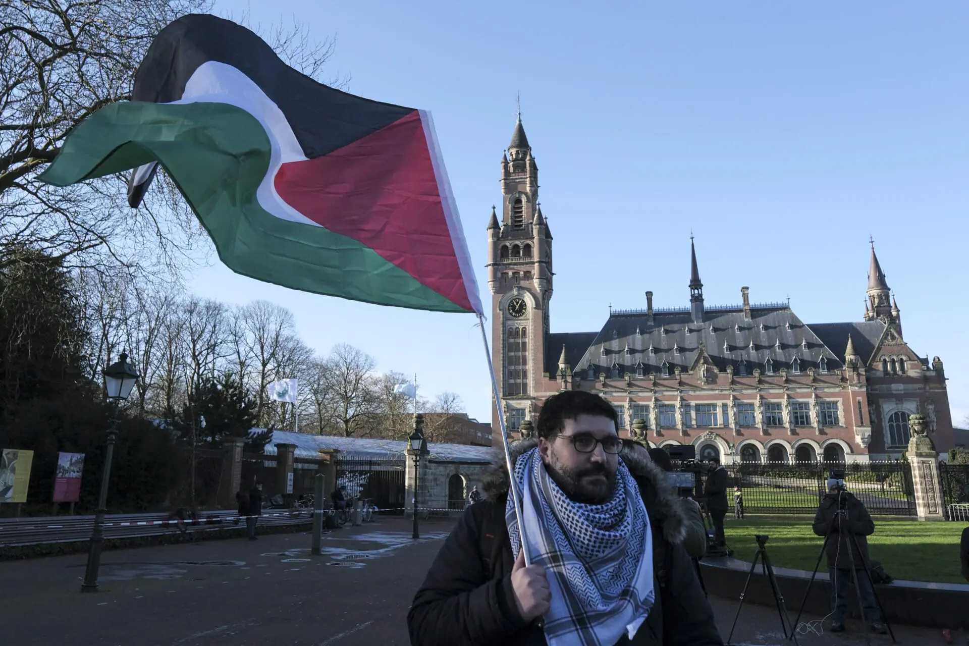 A protester waving the Palestinian flag stands outside the Peace Palace, which houses the International Court of Justice, or World Court, in The Hague, Netherlands, Friday, Jan. 26, 2024. Israel is set to hear whether the United Nations' top court will order it