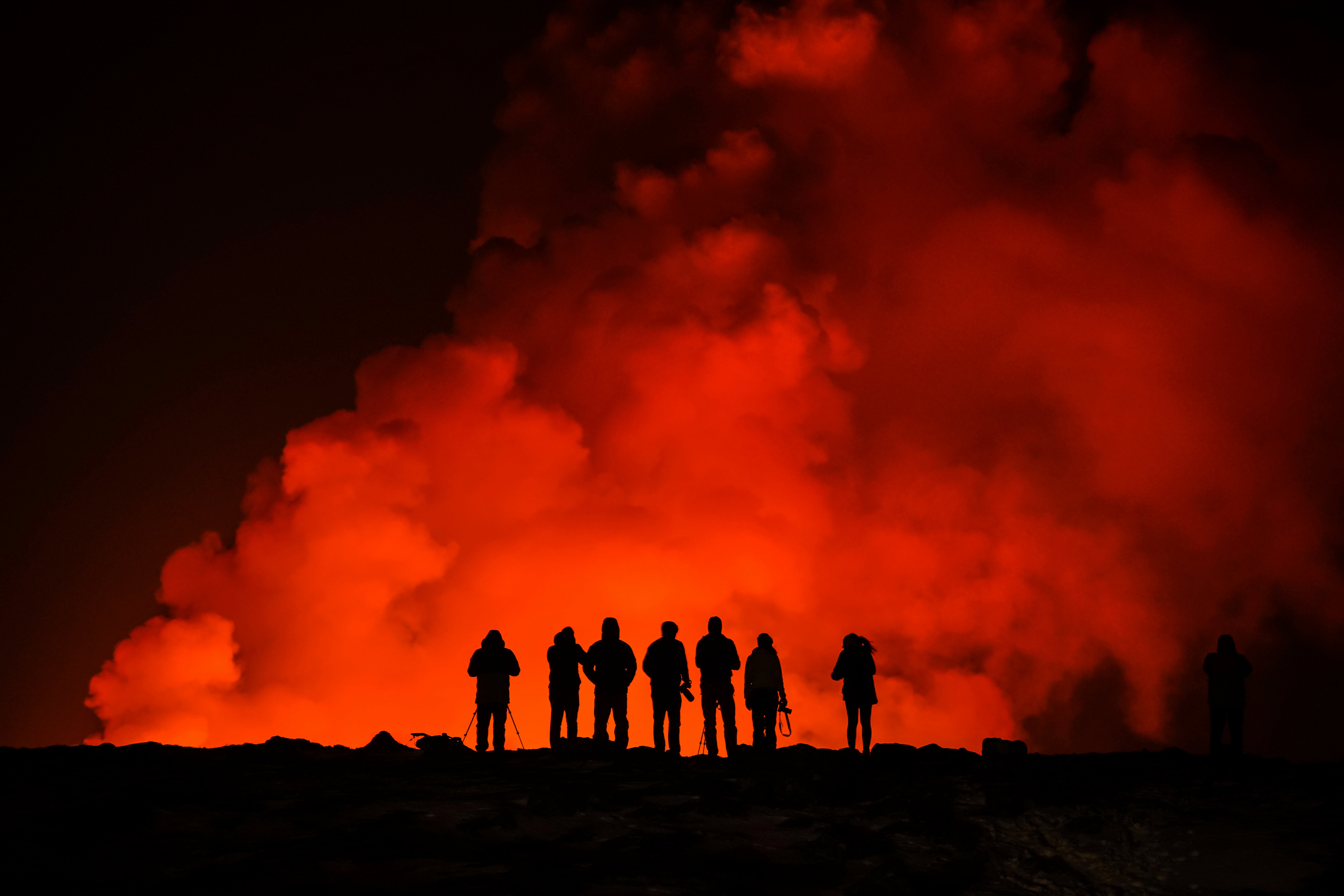 People look at the volcano erupting, north of Grindavík, Iceland, Thursday, Feb. 8, 2024. Iceland’s Meteorological Office says a volcano is erupting in the southwestern part of the country, north of a nearby settlement. The eruption of the Sylingarfell volcano began at 6 a.m. local time on Thursday, soon after an intense burst of seismic activity. (AP Photo/Marco Di Marco)