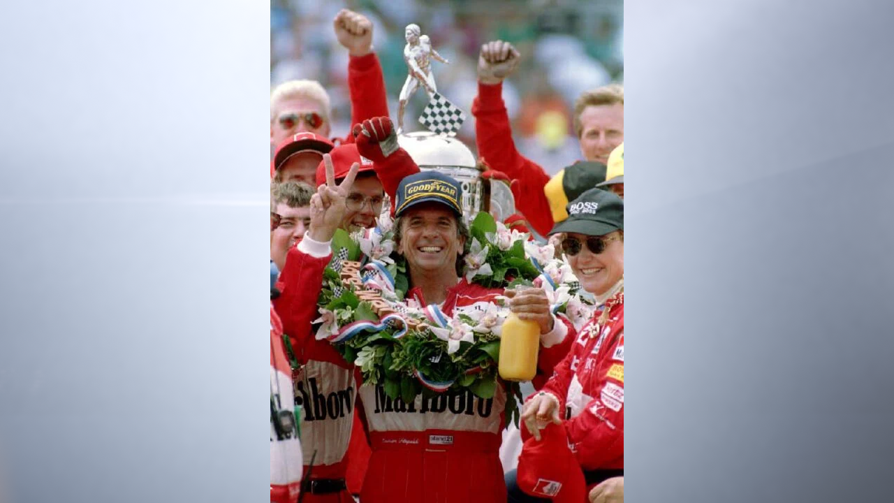 INDIANAPOLIS, IN - MAY 30: Brazil's Emerson Fittipaldi (C) celebrates his victory with wife Teresa(R) in the winner's circle 30 May 1993 after winning the the 1993 Indianapolis 500. Fittipaldi is raising two fingers to signify his second Indy 500 victory. (Photo by TODD PANAGOPOULOS/AFP via Getty Images)