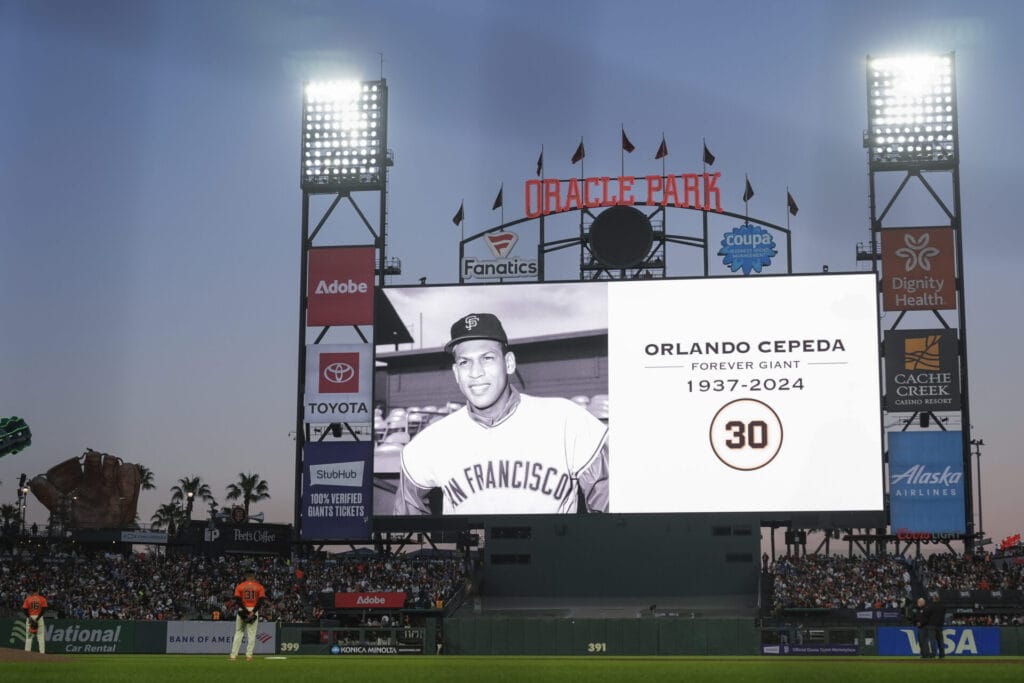 Players stand on the field as the San Francisco Giants announce the death of former baseball player Orlando Cepeda, before the sixth inning of the team's baseball game against the Los Angeles Dodgers, Friday, June 28, 2024, in San Francisco.