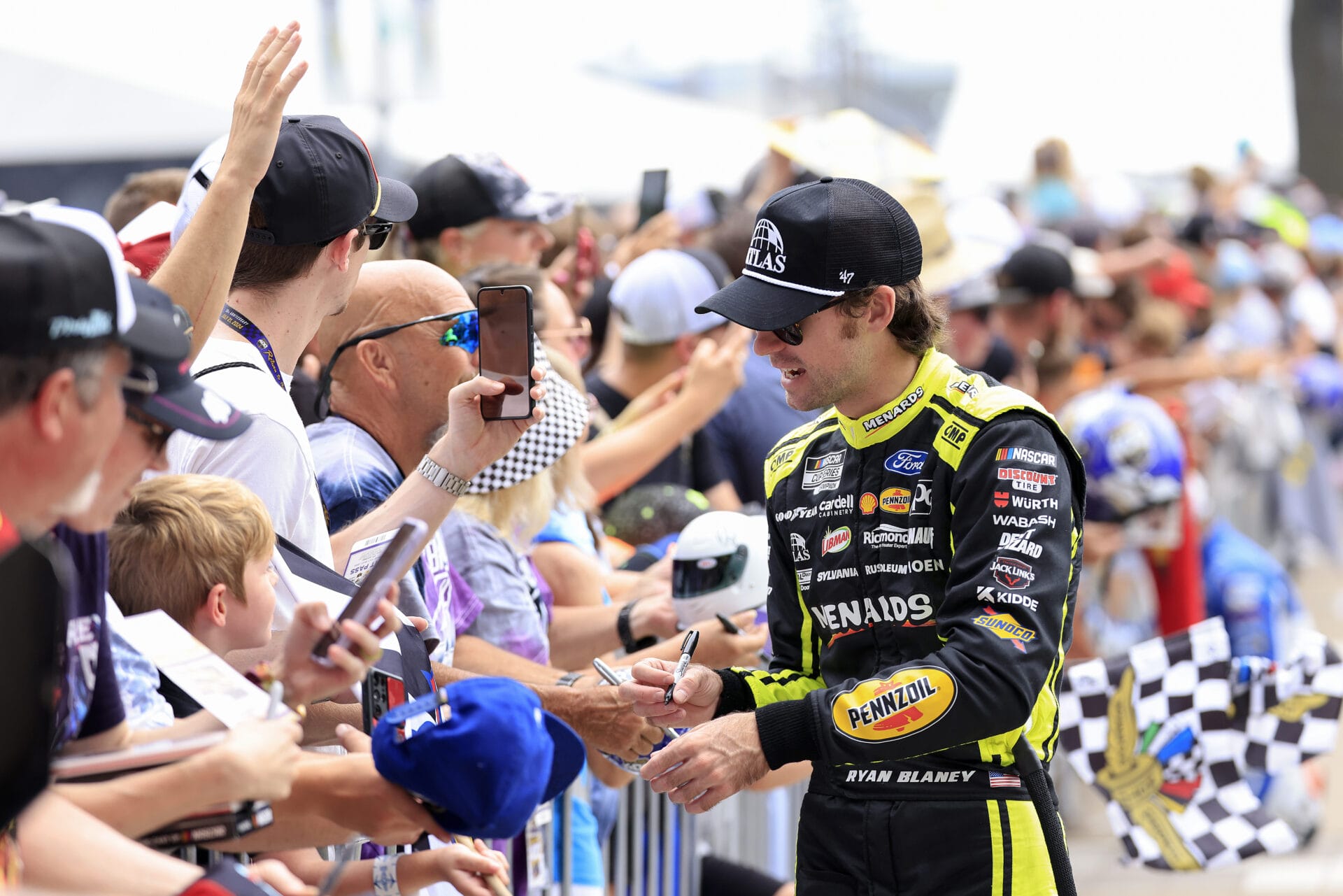 Ryan Blaney, driver of the #12 Menards/Atlas Ford, signs and autograph for a young NASCAR fans prior to the NASCAR Cup Series Brickyard 400 at Indianapolis Motor Speedway on July 21, 2024 in Indianapolis, Indiana. (Photo by Justin Casterline/Getty Images)