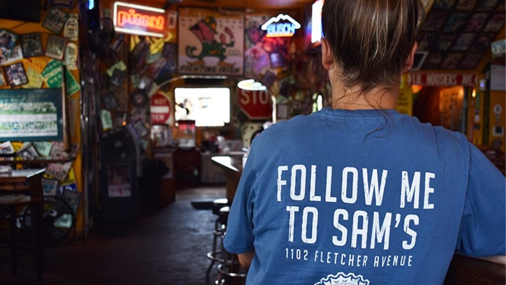An employee wearing a Sam's Silver Circle T-shirt with their slogan, "follow me to Sam's" on the back
