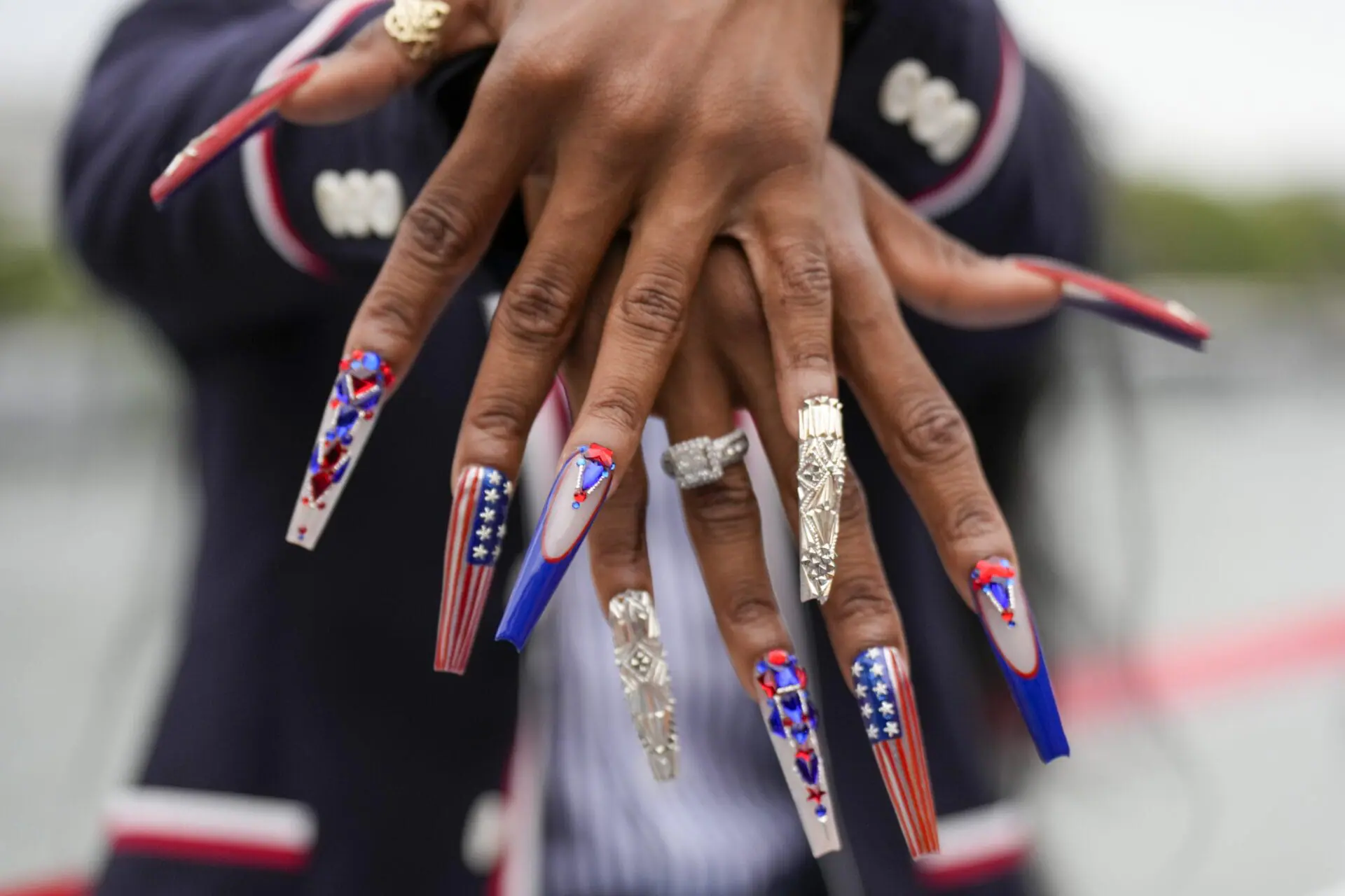 Athletes at the 2024 Paris Olympics are showing their team spirit with nail art that showcases their nation's flag and the Olympic rings. Sha'Carri Richardson, of the United States, shows off her nails while traveling along the Seine River in Paris, France, during the opening ceremony of the 2024 Summer Olympics, Friday, July 26, 2024. (AP Photo/Ashley Landis,Pool)