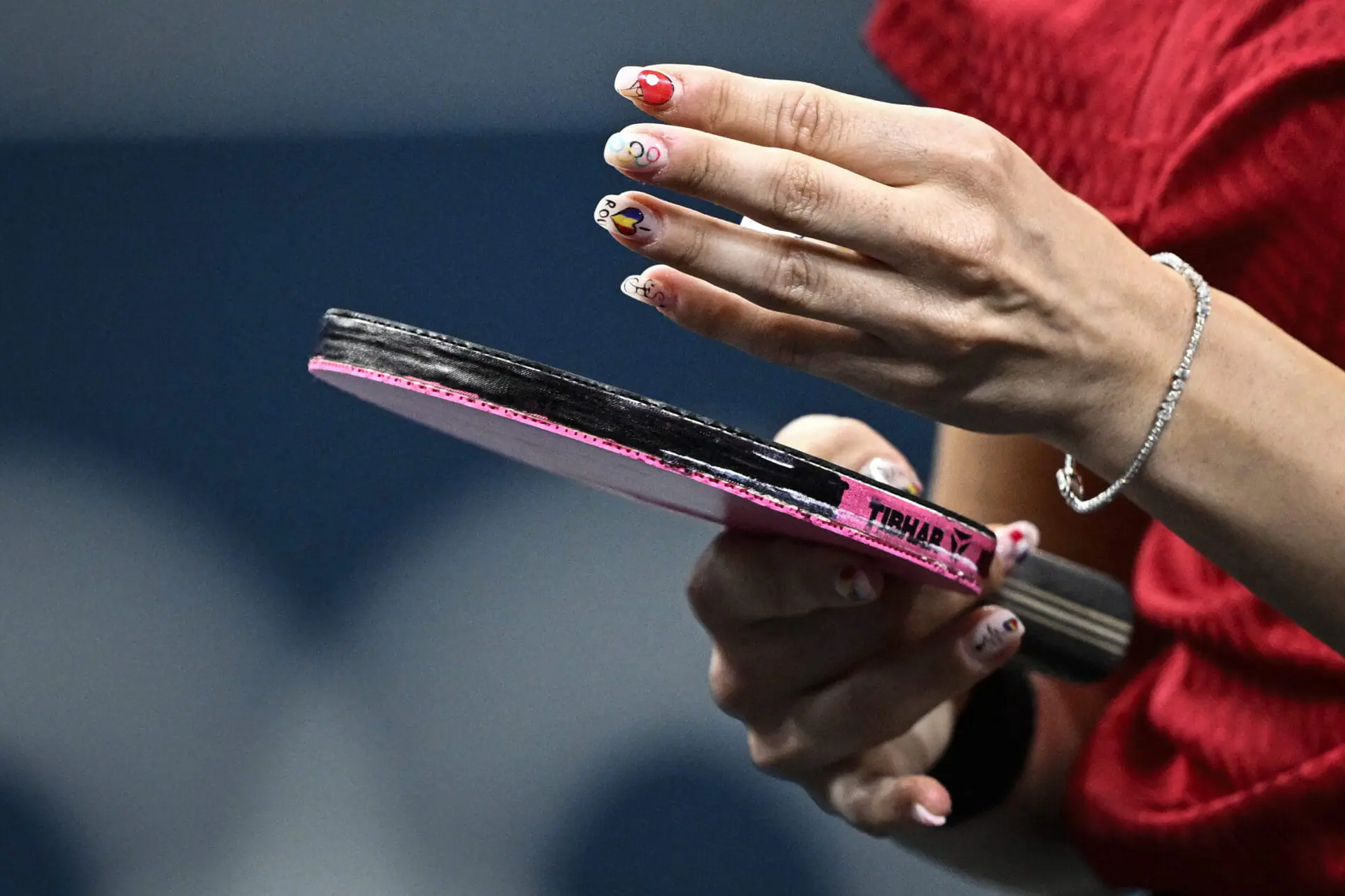 The nails of Romania's Bernadette Szocs depicting a table tennis racket, the Olympic Rings and Romania's national flag are pictured during her mixed table tennis doubles quarter-final with Romania's Ovidiu Ionescu against South Korea's Lim Jonghoon and South Korea's Shin Yubin at the Paris 2024 Olympic Games at the South Paris Arena in Paris on July 27, 2024. (Photo by WANG Zhao / AFP) (Photo by WANG