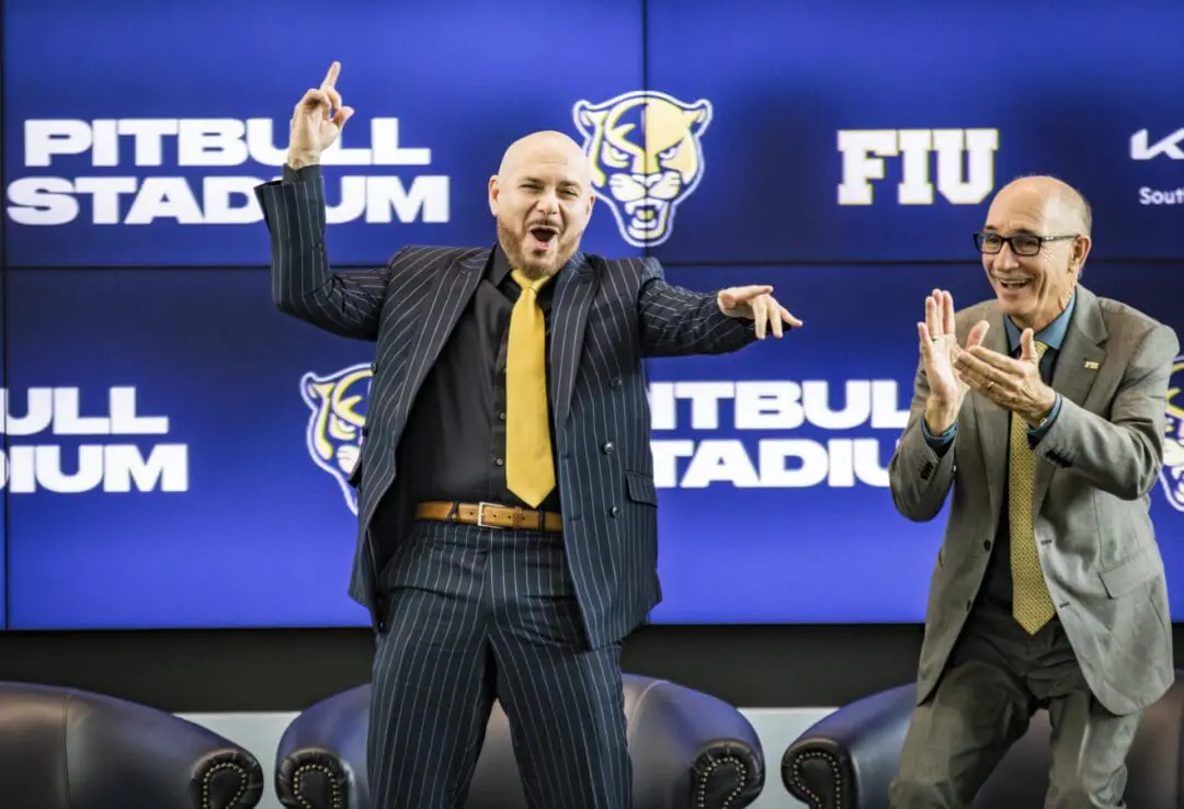 Cuban-American recording artist Pitbull, left, appears at a press conference announcing an athletic partnership with Florida International University at Tamiami Hall in Miami, Fla., on Tuesday, Aug. 6, 2024. Looking on at right is FIU President Kenneth Jessell. (Sophia Bolivar/Miami Herald via AP)