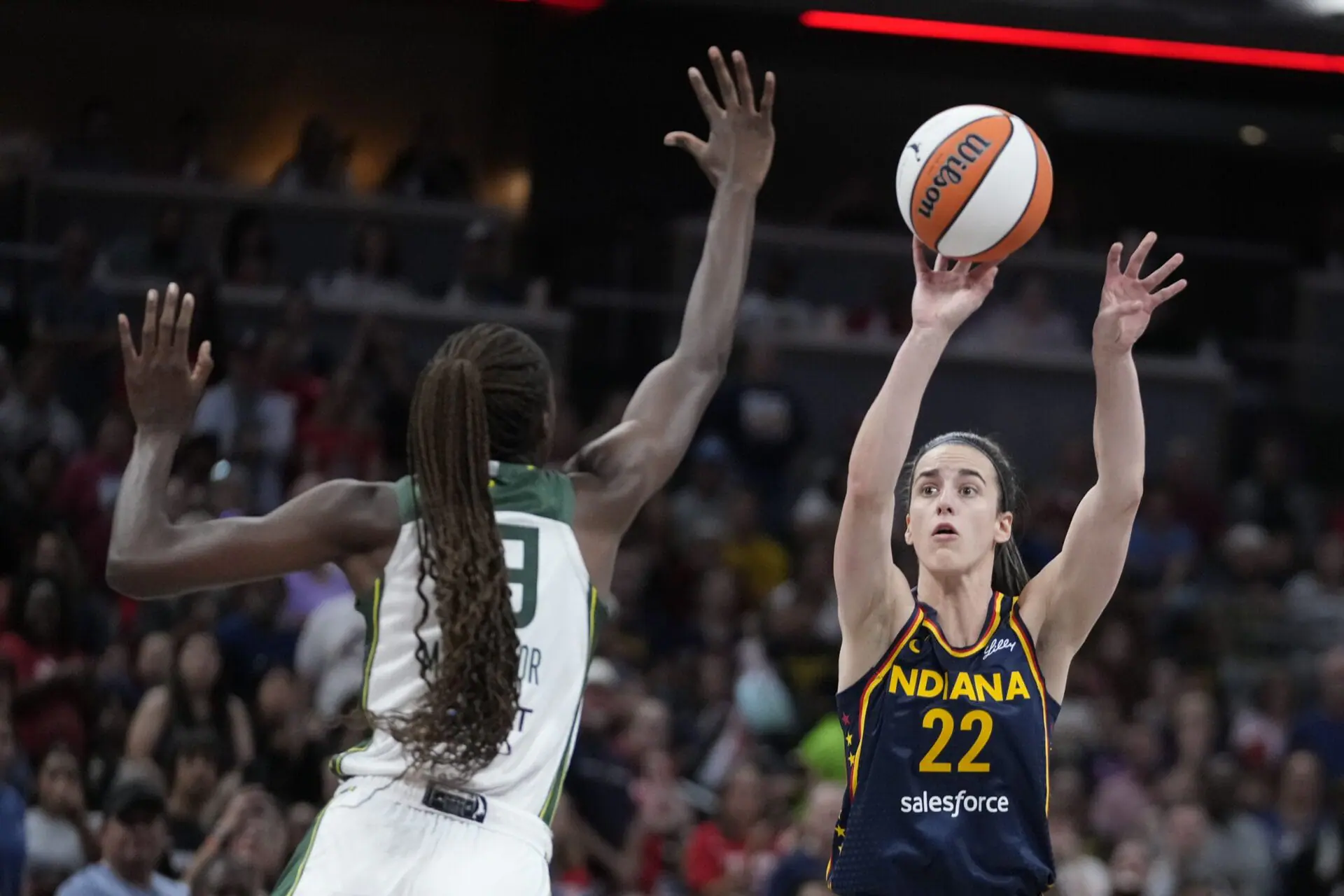 Indiana Fever's Caitlin Clark (22) shoots over Seattle Storm's Ezi Magbegor, left, during the first half of a WNBA basketball game, Sunday, Aug. 18, 2024, in Indianapolis. Three months into her WNBA career, the answer as to whether she could handle the transition to the pros is clear. (AP Photo/Darron Cummings)