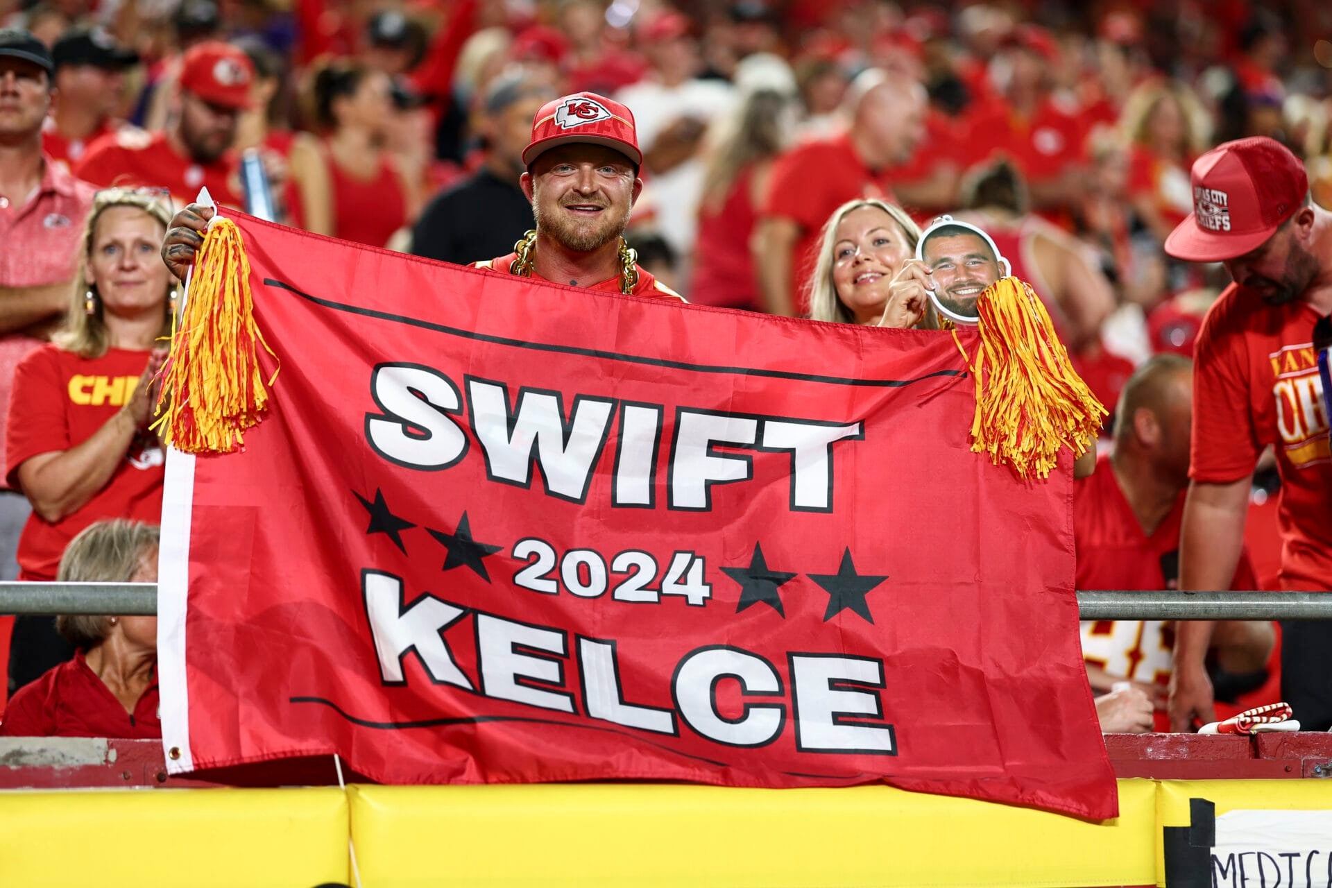 Kansas City Chiefs fans hold a flag for Taylor Swift and Travis Kelce during the third quarter of an NFL football game against the Baltimore Ravens at GEHA Field at Arrowhead Stadium on September 5, 2024 in Kansas City, Missouri. (Photo by Kevin Sabitus/Getty Images)