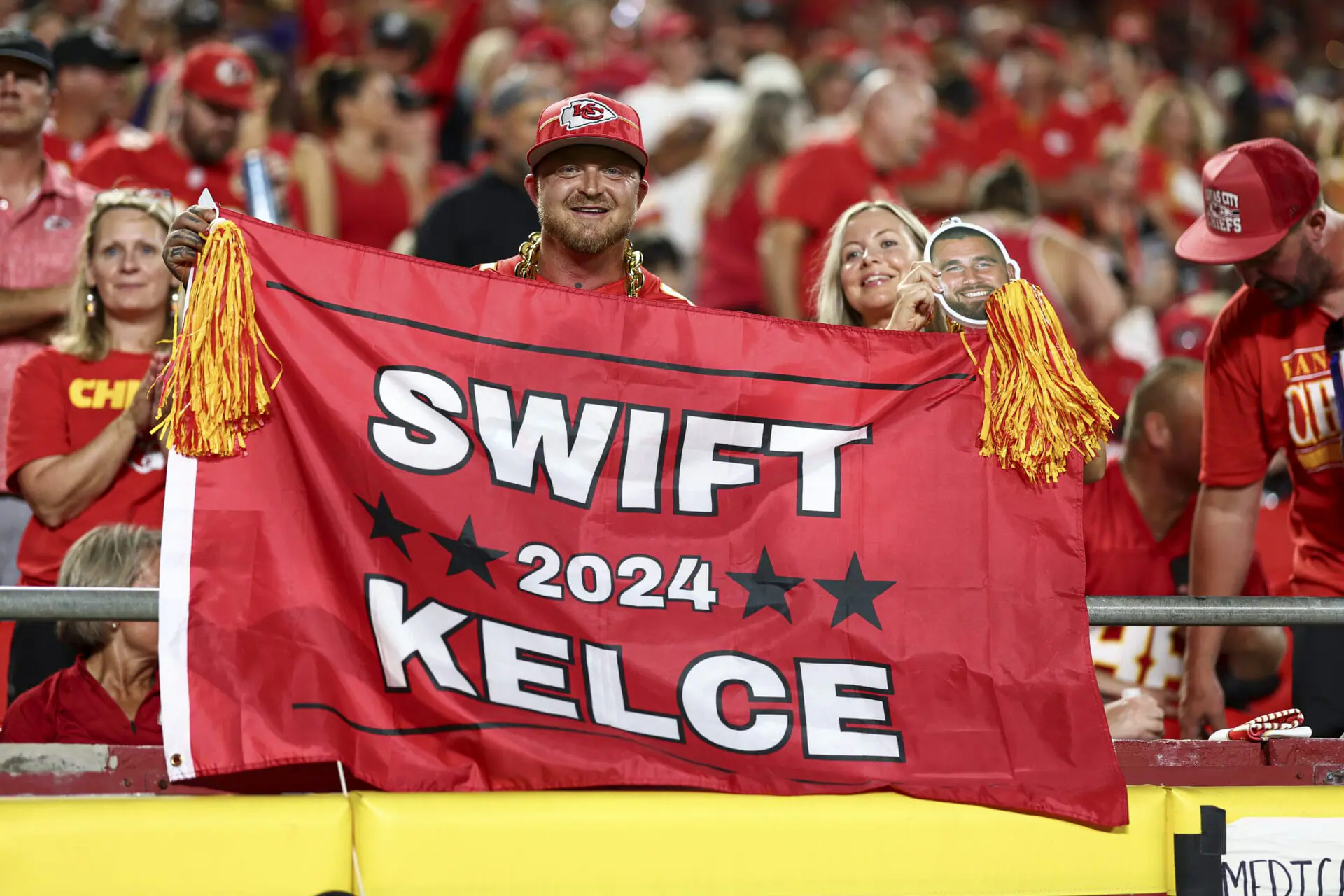 Kansas City Chiefs fans hold a flag for Taylor Swift and Travis Kelce during the third quarter of an NFL football game against the Baltimore Ravens at GEHA Field at Arrowhead Stadium on September 5, 2024 in Kansas City, Missouri. (Photo by Kevin Sabitus/Getty Images)