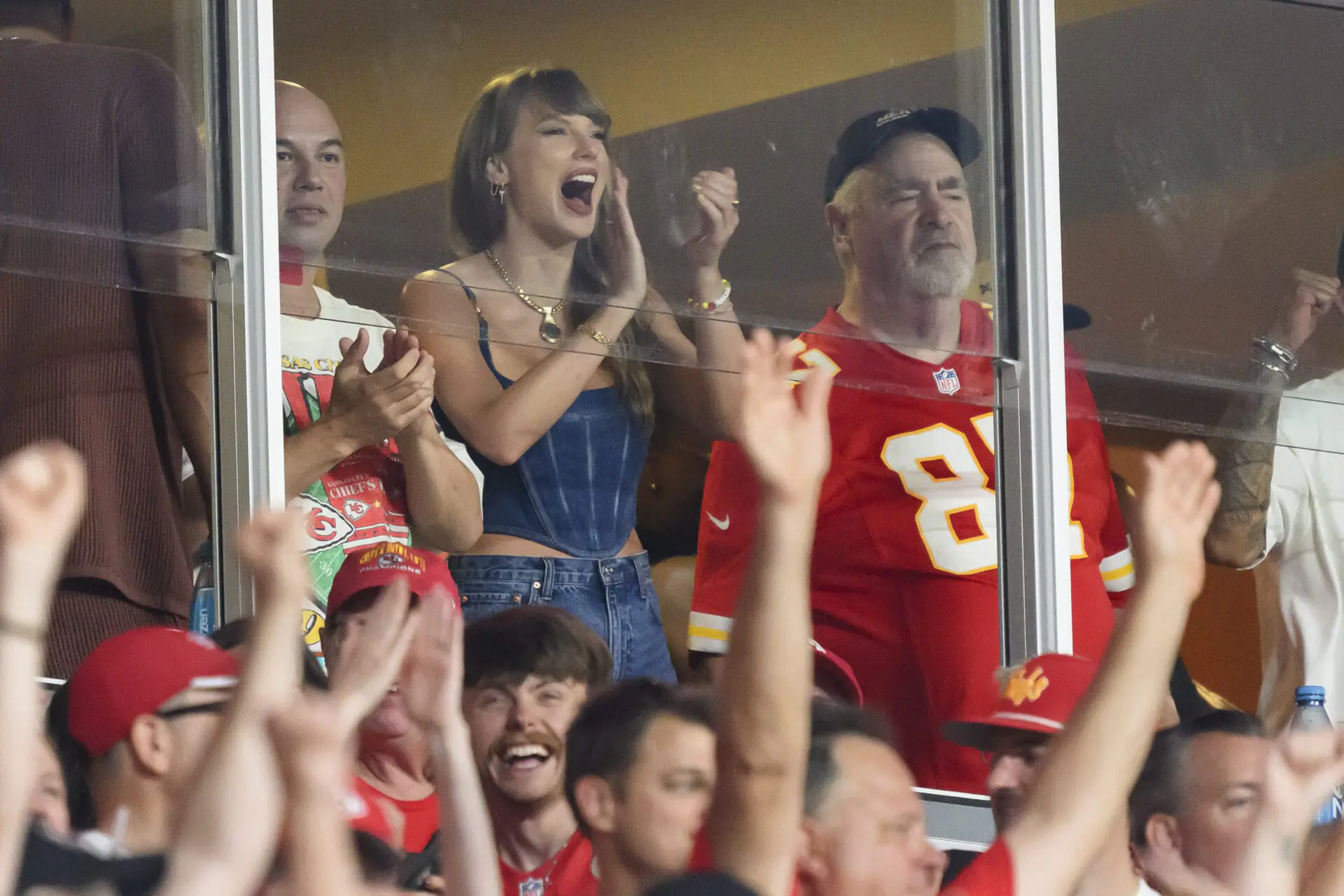 Taylor Swift, center, cheers a Kansas City Chiefs touchdown standing next to Ed Kelce, right, during the first half an NFL football gameagainst the Baltimore Ravens, Thursday, Sept. 5, 2024 in Kansas City, Mo. (AP Photo/Reed Hoffmann)