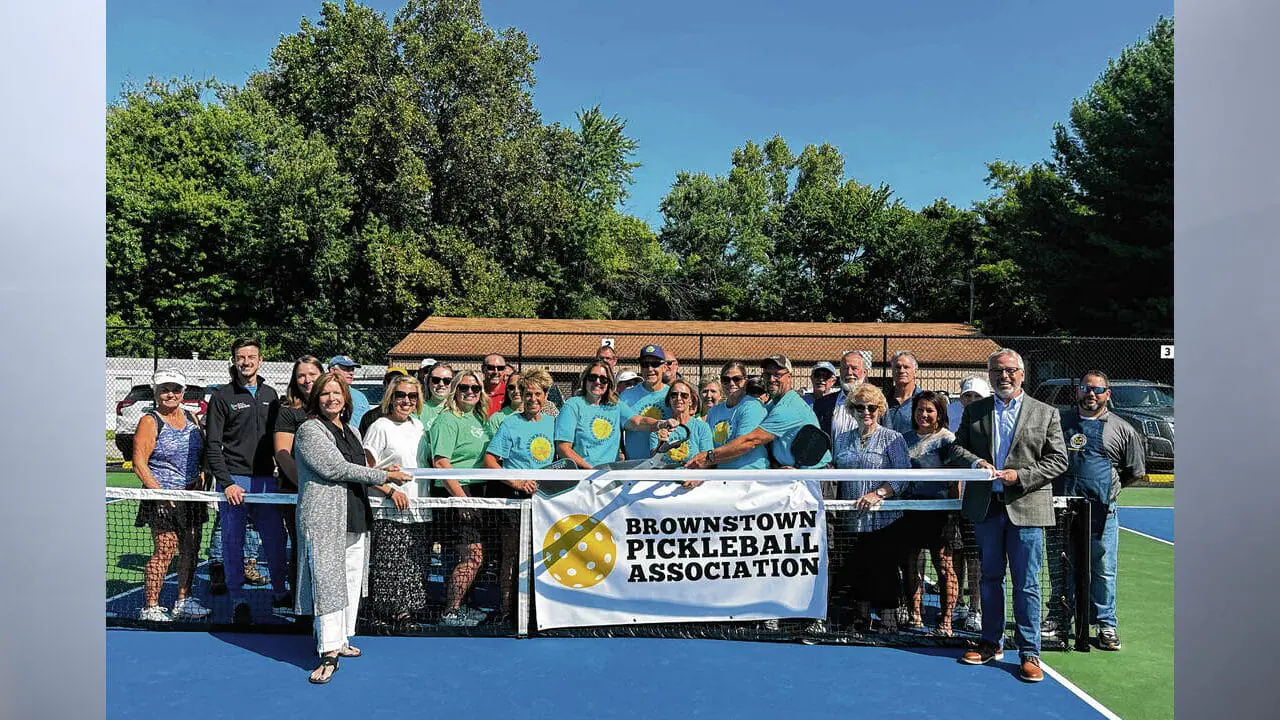 Community members and donors pose for a picture before the ribbon is cut on the new pickleball courts in the Brownstown Park. (Photo by Erika Malone/The Tribune)