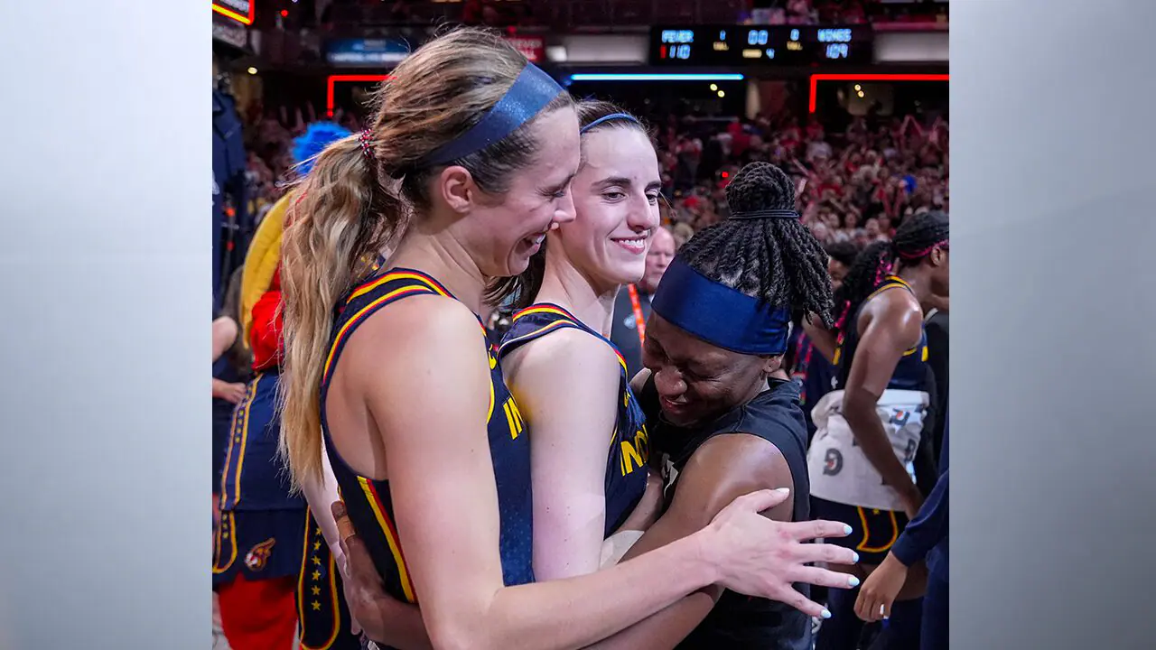 Indiana Fever guard Caitlin Clark, center is hugged by Lexie Hull, left, and Erica Wheeler (17) after a WNBA basketball game against the Dallas Wings in Indianapolis, Sunday, Sept. 15, 2024. (AP Photo/Michael Conroy)