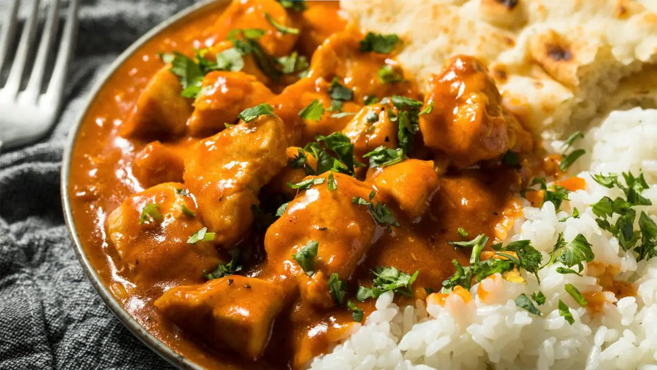 Chicken tikka masala garnished with cilantro, served with rice and naan