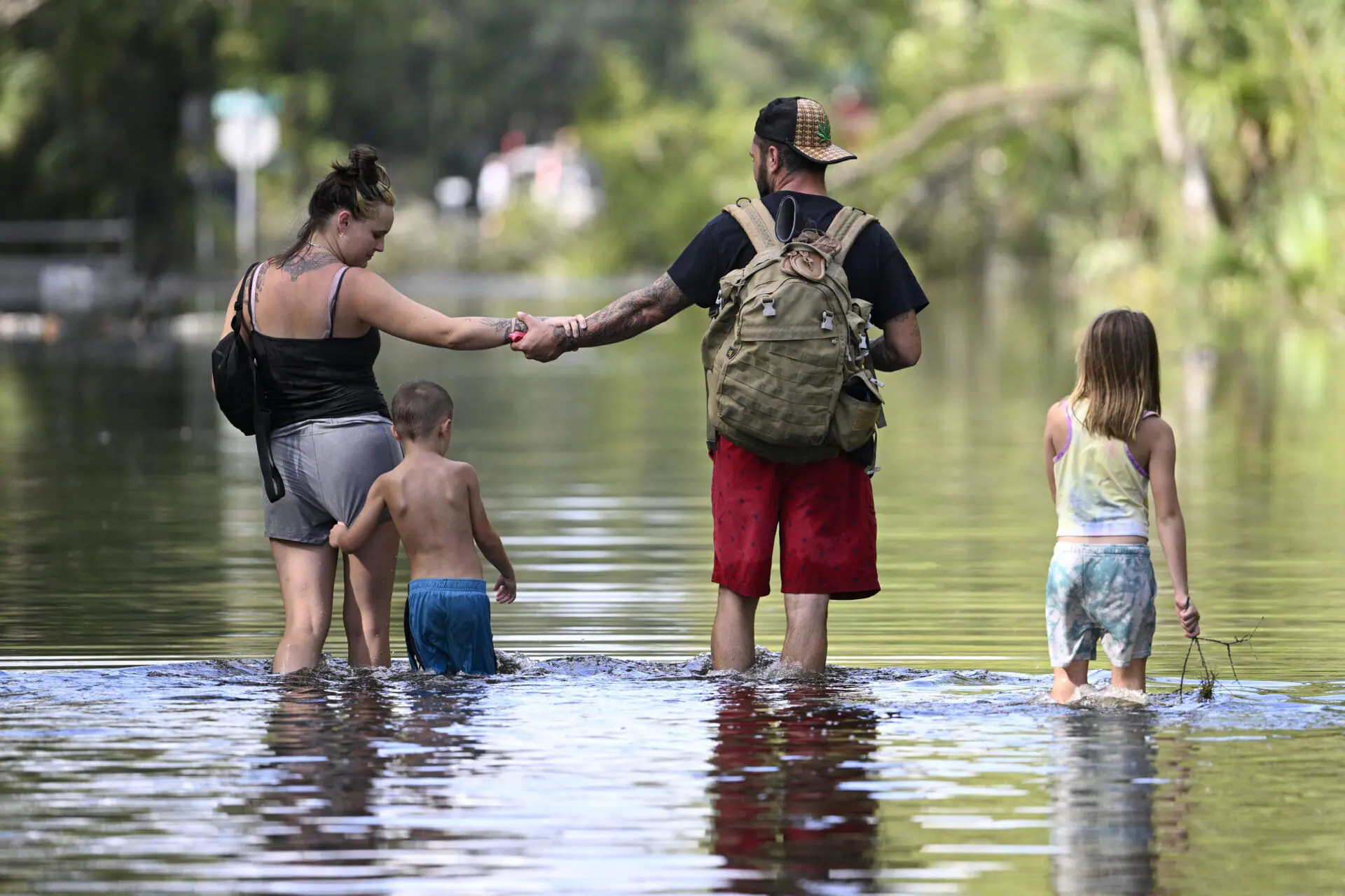 Dustin Holmes, second from right, holds hands with his girlfriend, Hailey Morgan, while returning to their flooded home with her children Aria Skye Hall, 7, right, and Kyle Ross, 4, in the aftermath of Hurricane Helene, Friday, Sept. 27, 2024, in Crystal River, Fla. (AP Photo/Phelan M. Ebenhack)