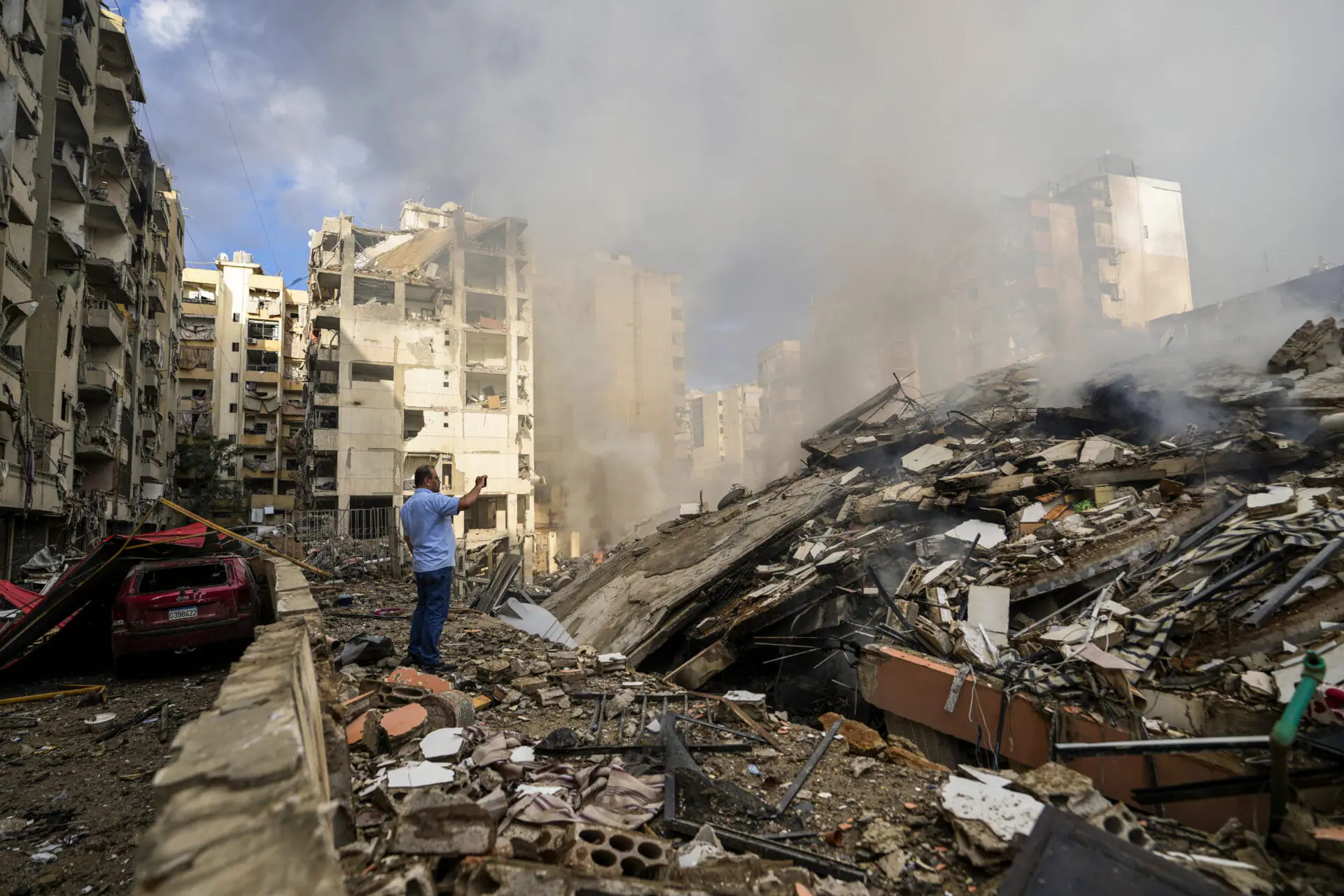 A man documents the damaged buildings at the site of an Israeli airstrike in Beirut's southern suburb, Lebanon, Tuesday, Oct. 1, 2024. (AP Photo/Hassan Ammar)