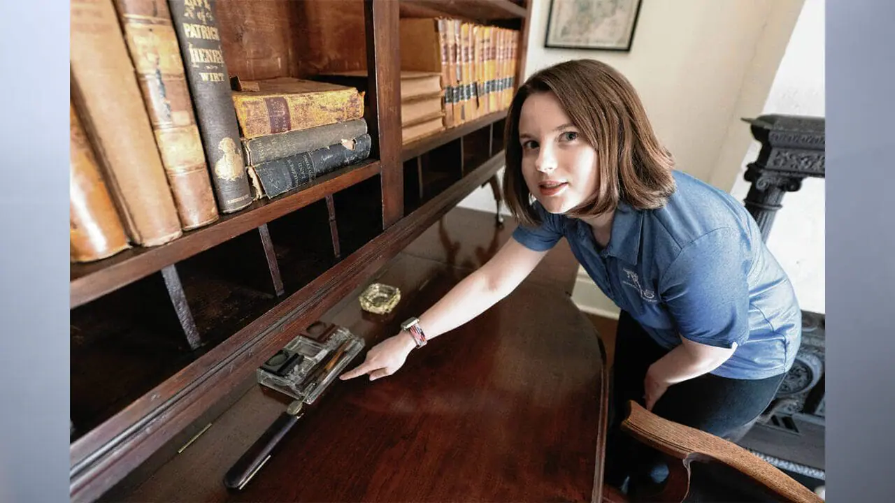 Marissa Purcell stands next to the desk used by Hoosier poet James Whitcomb Riley at the Riley Home in Greenfield. Purcell is its first museum curator and works closely with the Riley Old Home Society to care for historic artifacts in the home and neighboring museum. (Photo by Tom Russo/Daily Reporter)