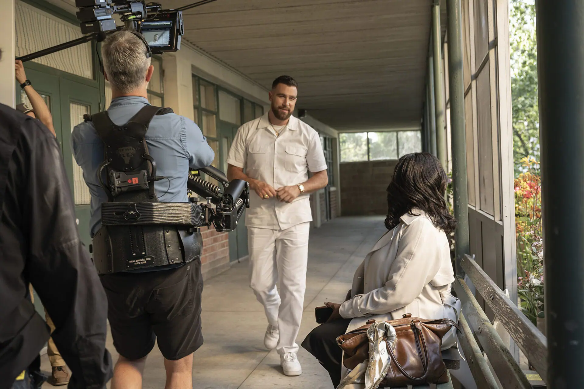 This image released by FX shows Travis Kelce, center, and Niecy Nash, right, during the filming of the series 