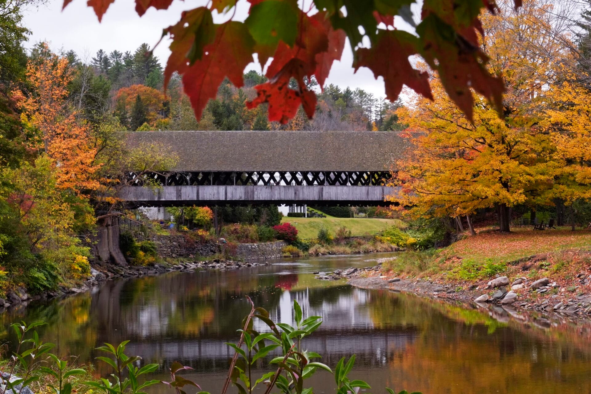 Trees changing to Autumn colors surround the Middle Covered Bridge, which spans the Ottauquechee River, Tuesday, Oct. 15, 2024, in Woodstock, Vt. (AP Photo/Charles Krupa)