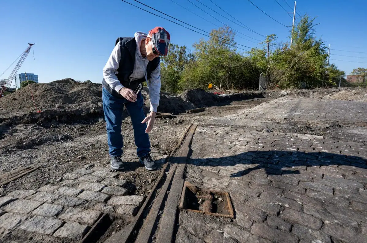 Ron Darrah, with the Genealogical Society of Marion County, examines parts of the railway and pavers that have been unearthed at the Henry Street Bridge construction site, Oct. 17, 2024, on the grounds of the historic Greenlawn cemeteries.