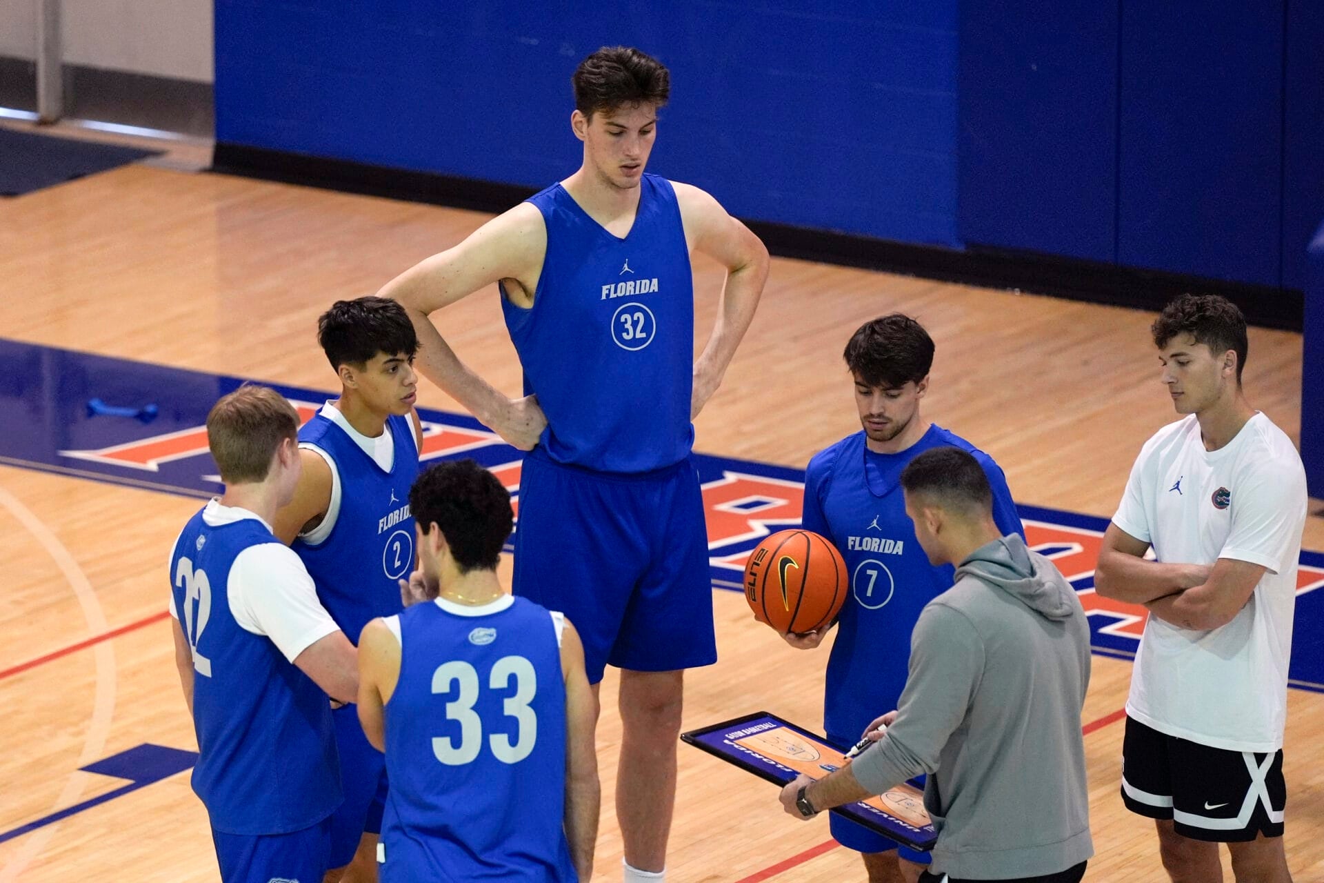 Olivier Rioux, back center, a 7-foot-9 NCAA college basketball player at Florida, gathers with coaches and teammates at the team's practice, Friday, Oct. 18, 2024, in Gainesville, Fla. (AP Photo/John Raoux)