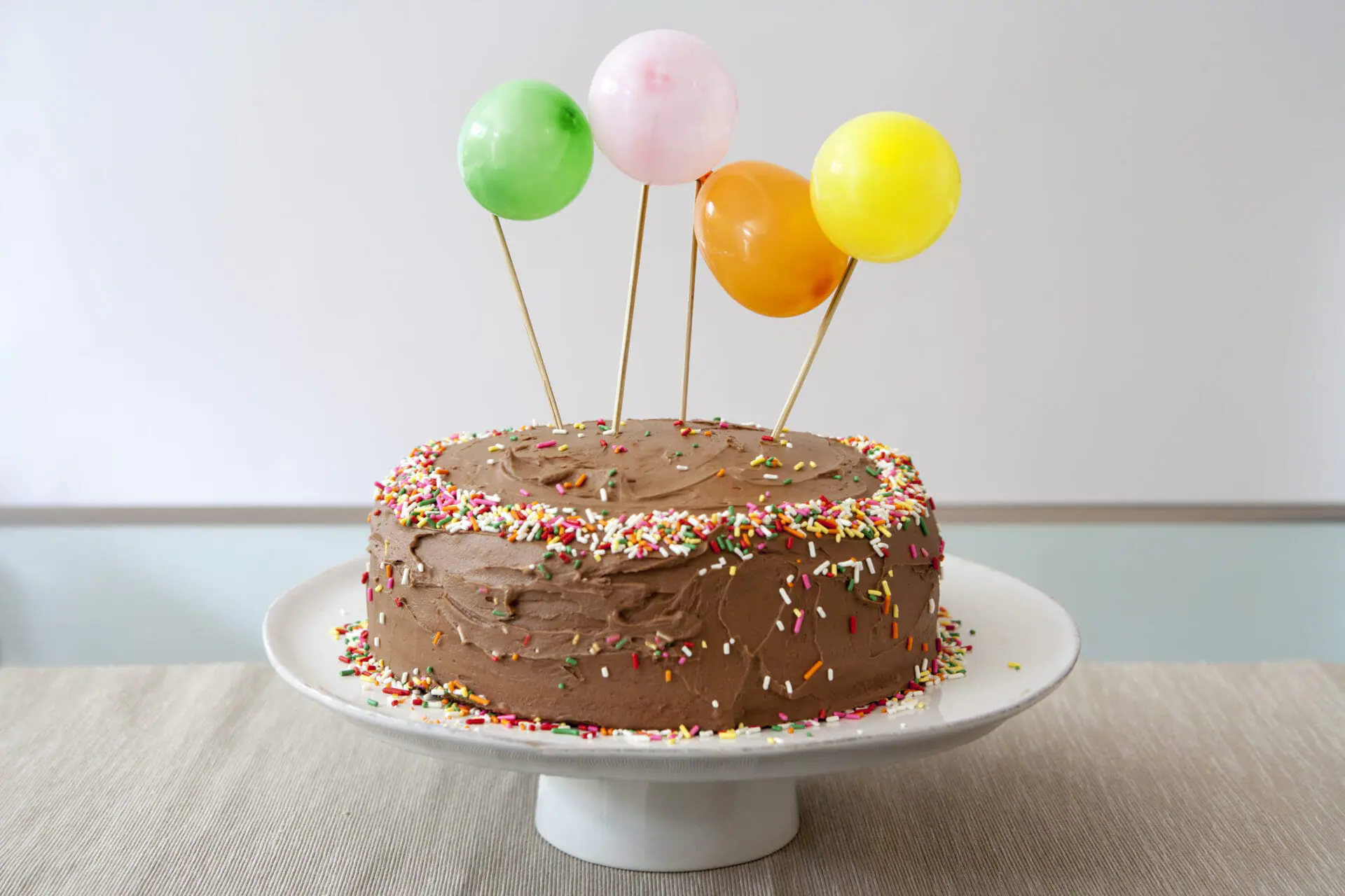 Birthday Cake with Chocolate Icing Decorated with Balloons and Sprinkles. (Photo by: Education Images/Universal Images Group via Getty Images)