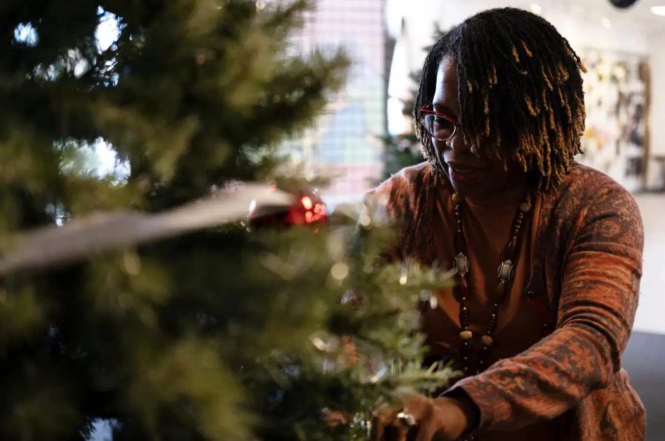 Kimberly Rusununguko, of the Delta Sigma Theta sorority, hangs decorations on a tree at Indy's Global Village on Nov. 19, 2024. (Provided Photo/Enrique Saenz/Mirror Indy)