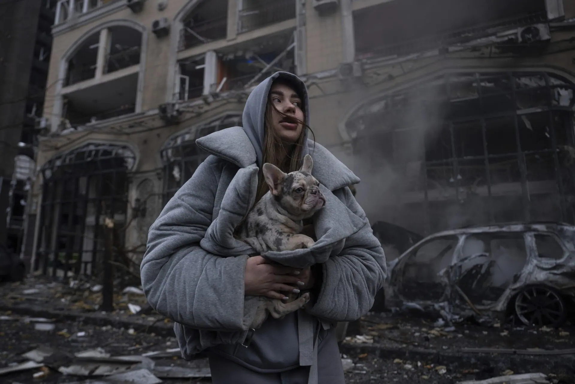 Ivanna warms her dog in front of a destroyed burning car after a recent Russian attack in Kyiv, Ukraine, Friday, Dec. 20, 2024. (AP Photo/Alex Babenko)