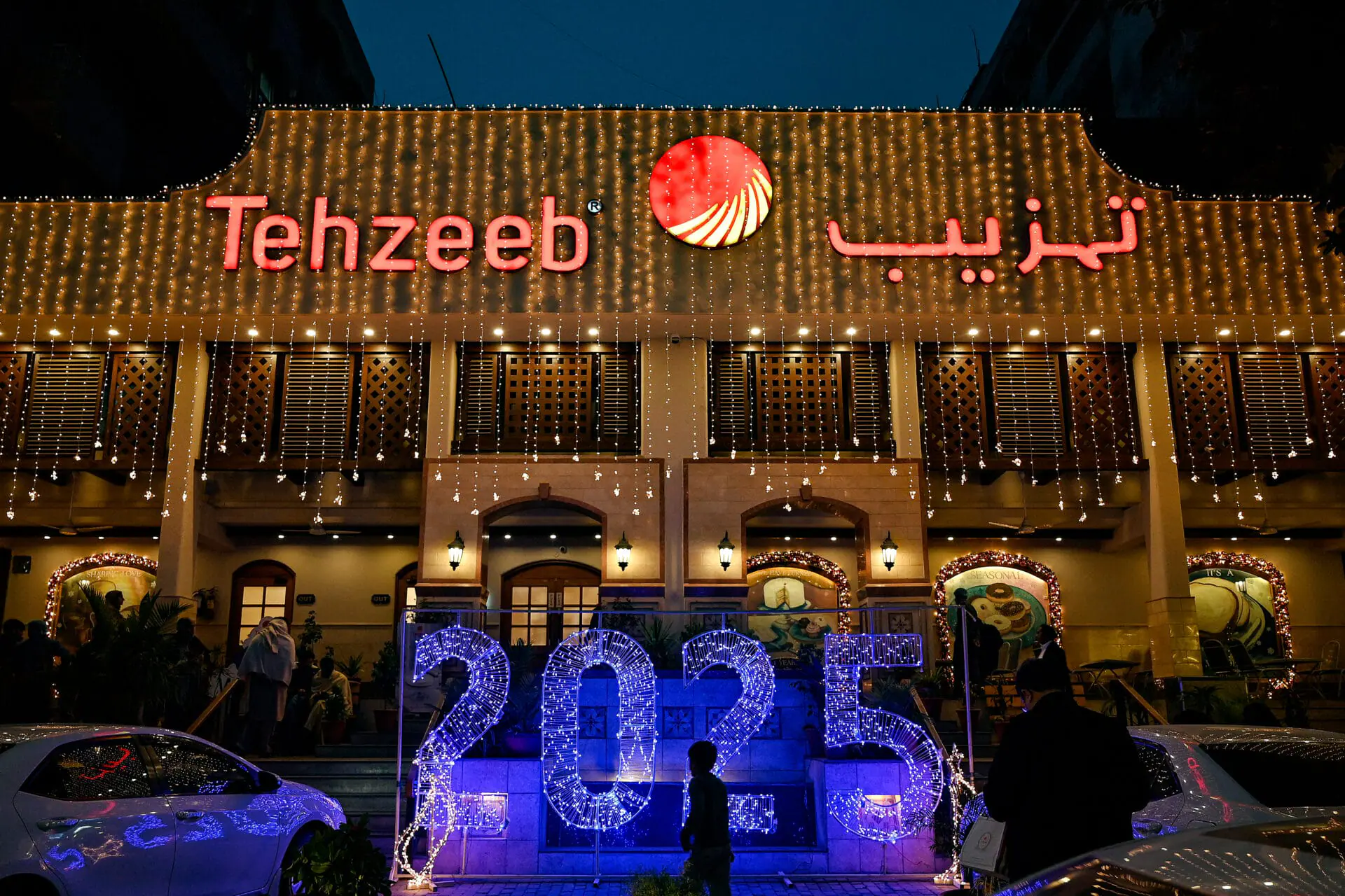 A man walks past an illuminated decoration displayed on New Year's Eve in Islamabad on December 31, 2024. (Photo by Aamir QURESHI / AFP) (Photo by AAMIR QURESHI/AFP via Getty Images)