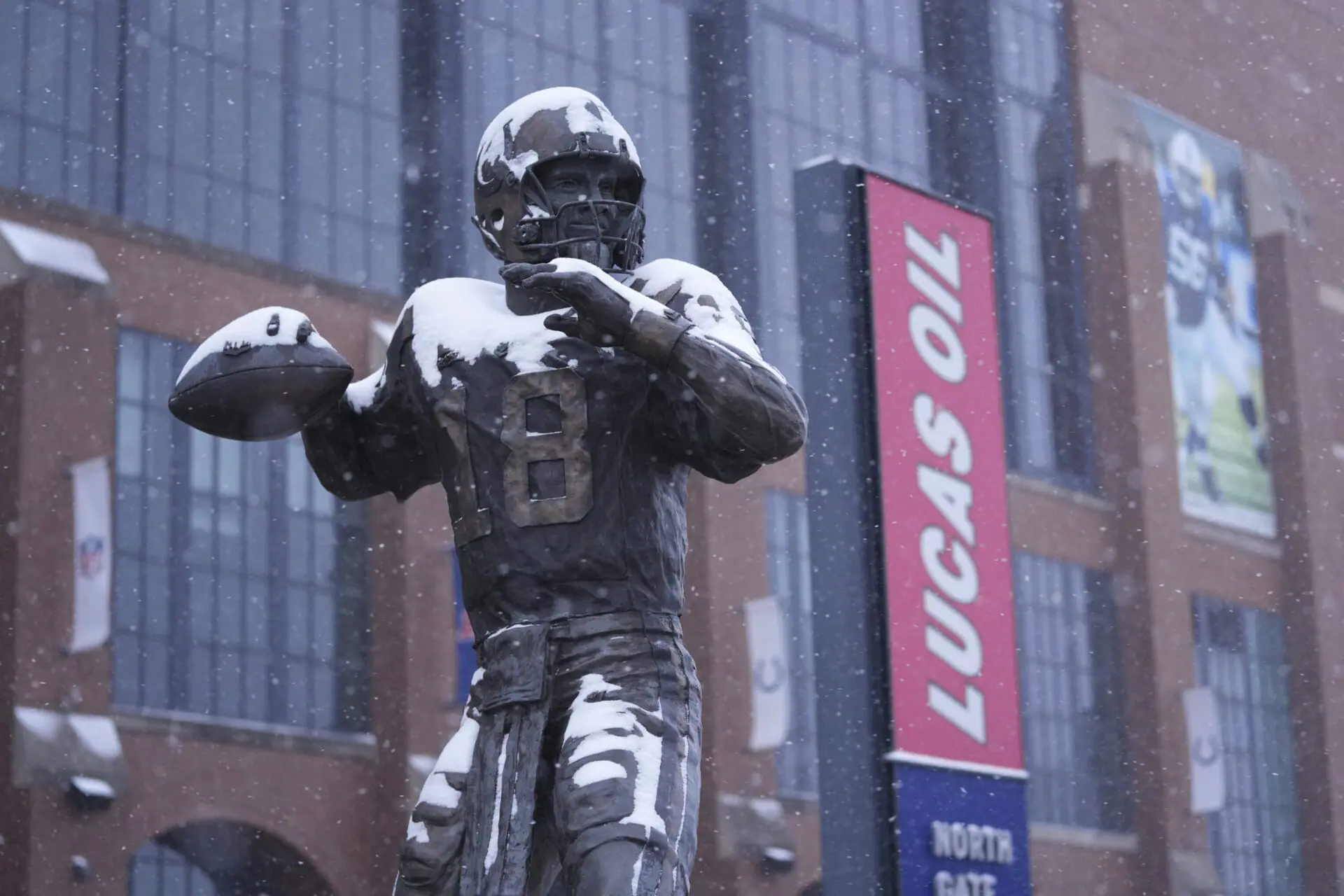 A statue of Peyton Manning by Ryan Feeney is dusted with snow outside Lucas Oil Stadium after an NFL football game between the Indianapolis Colts and the Jacksonville Jaguars, Sunday, Jan. 5, 2025, in Indianapolis. (AP Photo/Michael Conroy)