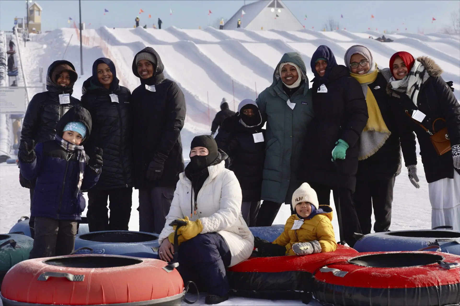 Nasrieen Habib, center right with green coat, and some of the members of the outdoors group she founded for Muslim women pose for a photo at the bottom of a snow tubing hill at Elm Creek Park Reserve in Maple Grove, Minn., on Jan. 4, 2025. (AP Photo/Mark Vancleave)